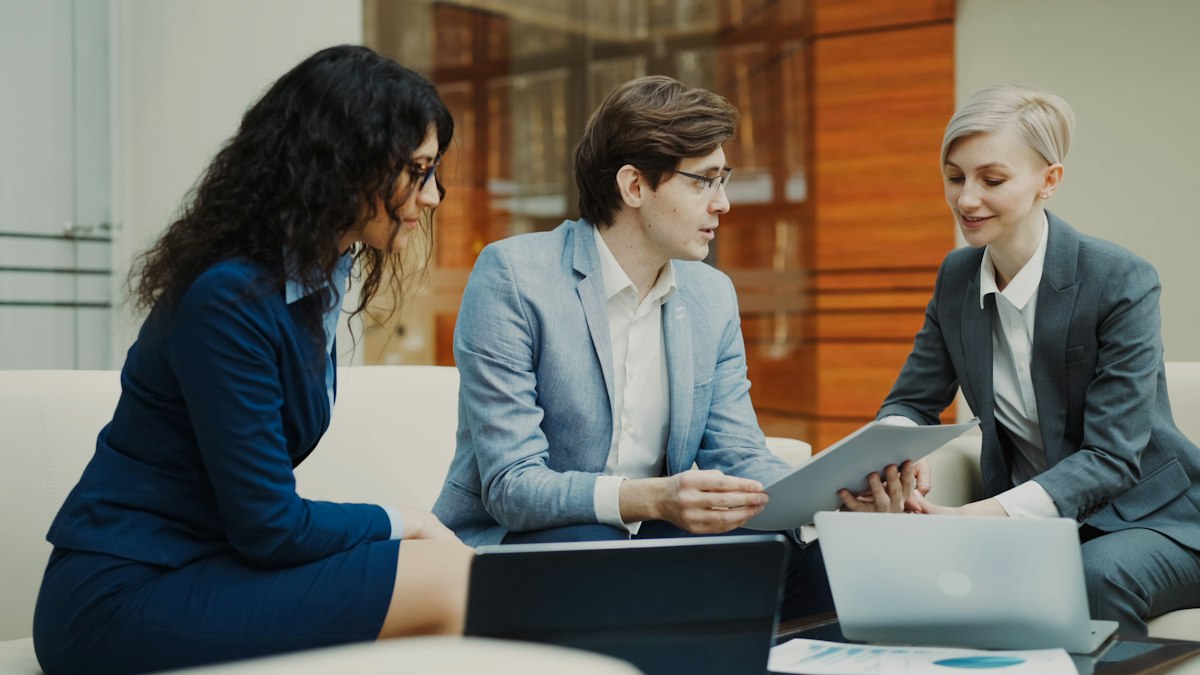 Three professionals discussing documents in a meeting